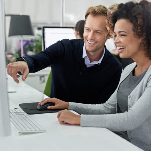 Man pointing something out to a female colleague on her computer screen.